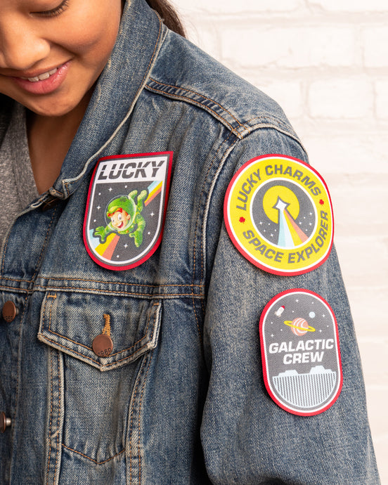 A girl wearing a denim jacket with 3 Lucky Charms™ Galactic Patches attached to shoulder area.